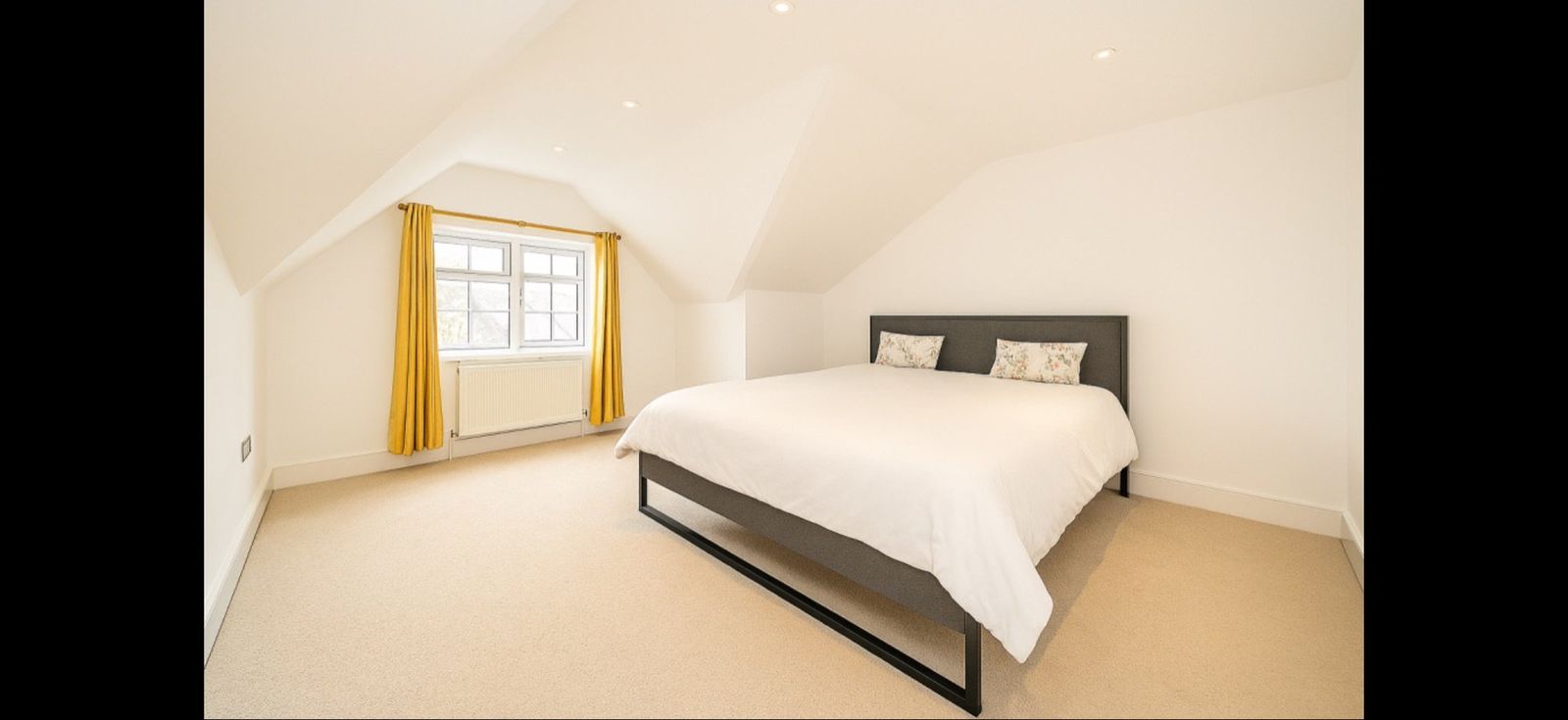 Attic-floor bedroom with sloped ceiling, mustard curtains, and a king bed