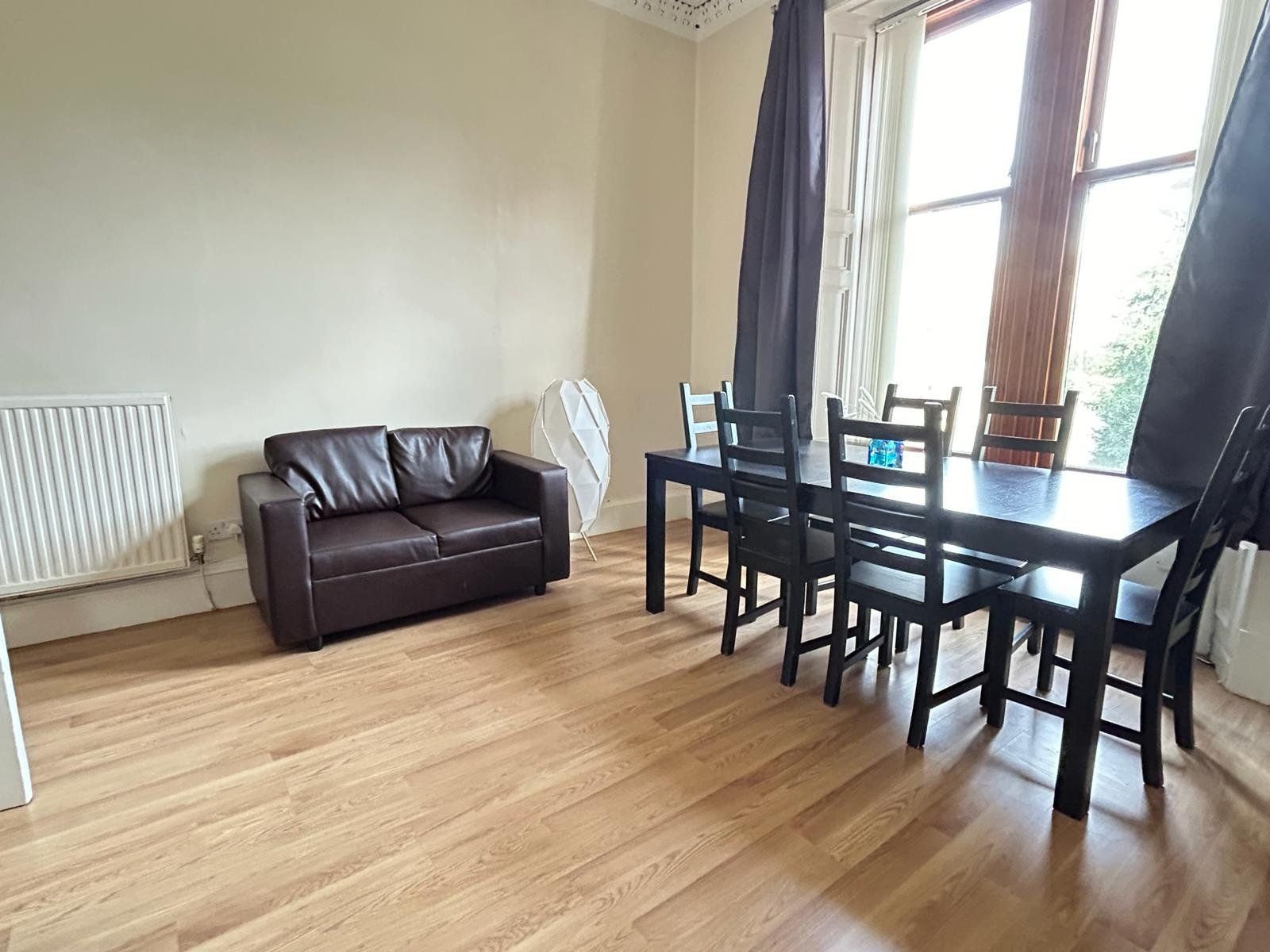 Living and dining room — leather sofa, six-seater dining table, tall sash windows opening onto Vicar Street